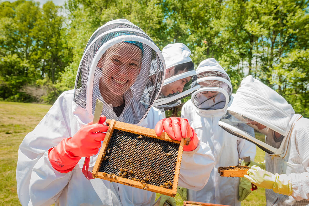 Student in bee gear holding comb