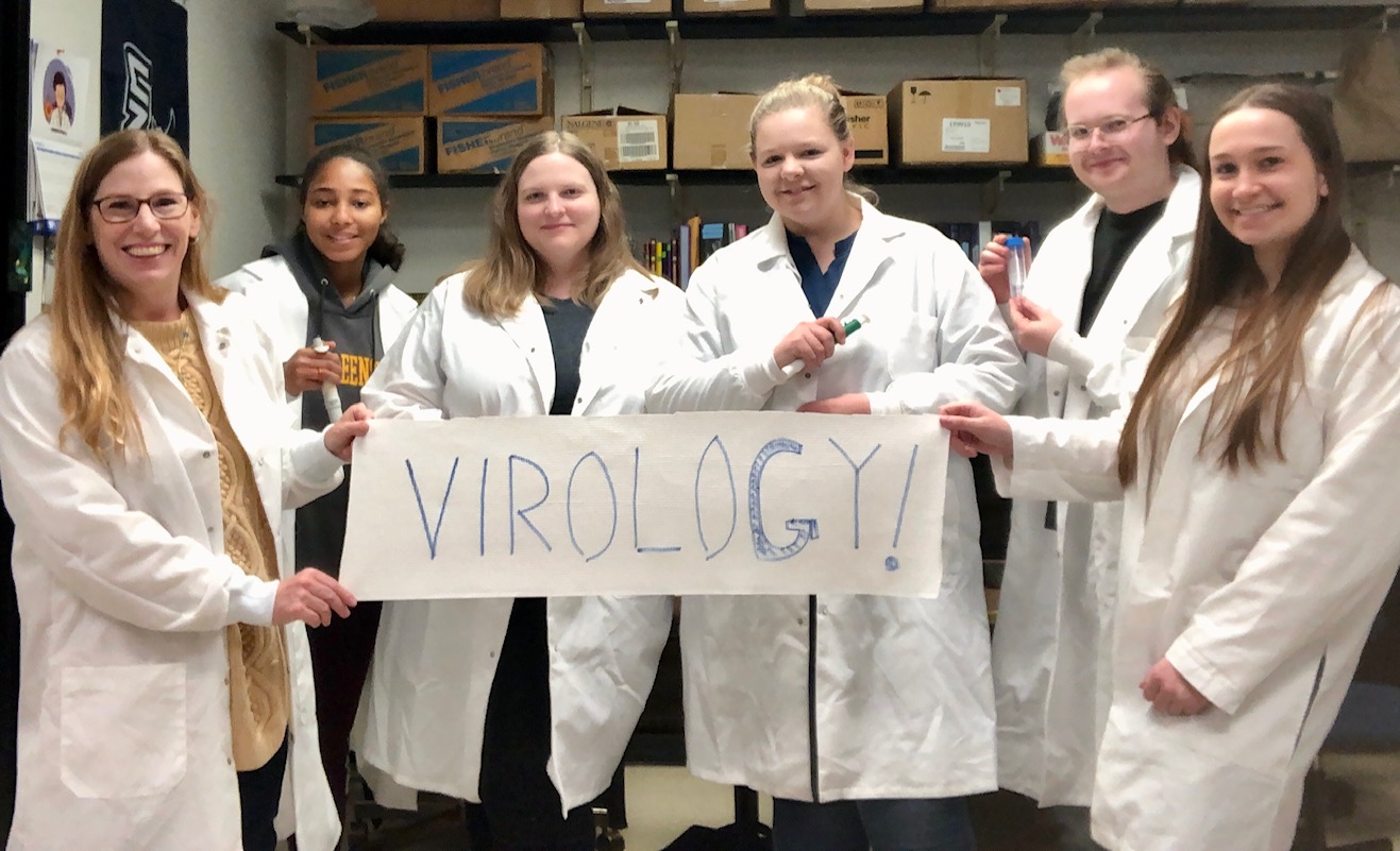 Adamson Research Group holding a sign that says VIROLOGY!